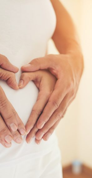 pregnant-woman-her-husband-hand-showing-heart-shape